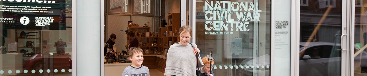 A woman and two young children with toy battle axes smile and laugh as they exit the doors of the National Civil War Centre